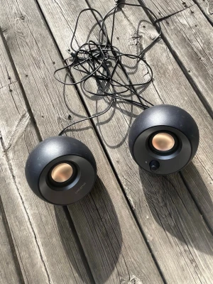 Svarta bärbara högtalare med USB - Säljer ett par runda, svarta bärbara högtalare med kopparfärgade detaljer. De ansluts via USB och 3,5 mm AUX-kabel, perfekt för dator eller laptop. Snygg och modern design som passar på skrivbordet. Tillverkade i plast.