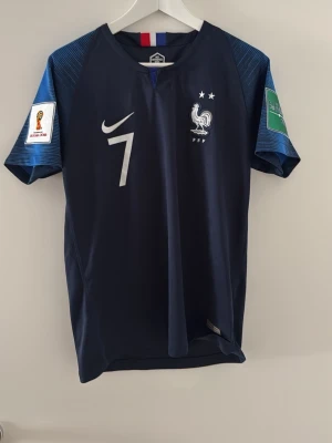 Frankrike VM 2018 tröja  - Mörkblå officiell Frankrike fotbollströja från Nike med Griezmann och nummer 7 på ryggen. Tröjan har båda VM badger på armarna och är i Storlek S. Säljer den för 600kr då den är äkta