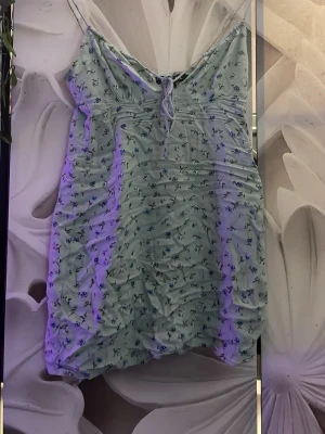 Ljusblå blommig kort klänning - Söt ljusblå kort klänning med tunna axelband och små blommor i blått. Klänningen har snörning framtill och är lätt rynkad för en cool look. Perfekt för varma dagar och sommarhäng.
