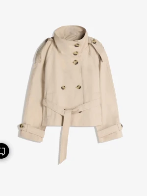 Bershka trenchcoat  - Stilren kort trenchcoat i beige med dubbelknäppning, axelklaffar och bälte i midjan. Jackan har klassiska detaljer som knappar på ärmsluten och hög krage. Perfekt för en trendig och tidlös look. Aldrig använd i storlek L