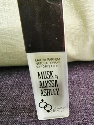 Musk by Alyssa Ashley parfym 25 ml - Musk by Alyssa Ashley är en eau de parfum i en stilren, frostad glasflaska med svart fyrkantigt lock. Flaskan rymmer 25 ml och har en enkel, klassisk design med svart text och symboler på framsidan.