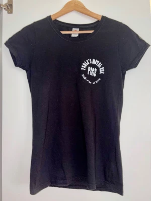 Svart t-shirt Paule's Metal Eck - Säljer en svart t-shirt med tryck från Paule's Metal Eck, en metalpub i Berlin. — T-shirten har rund hals, korta ärmar och vit text både fram och bak. — Materialet är av bomull och passformen är åt det mer åtsittande hållet. — Perfekt för dig som gillar rockiga detaljer. — Sparsamt använd, i mycket bra skick. — Nypris ca. 300 kr.