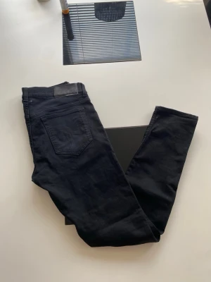 Svarta slim jeans 32/34 - Snygga svarta slim fit jeans med klassisk femficksdesign och raka ben. Tillverkade i Italien och har en stilren look som passar till det mesta. Jeansen har en diskret svart patch vid linningen och är perfekta för dig som gillar en smalare passform.