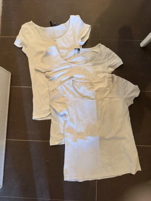 3 vita bas-tshirts med rund hals - Tre klassiska vita t-shirts med rundad halsringning och korta ärmar. Perfekta som basplagg till alla outfits. Tillverkade i mjuk bomull för skön känsla och enkel stil. Två från Vero Moda och en från lager 157. Om man vill köpa separat är det 15kr/styck. Skulle säga att alla sitter som S.