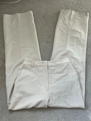  beige/vita kostymbyxor - Helt nya beige/vita kostymbyxor, prislappen är fortfarande kvar. Dem är aldrig använda! Dem är vida, i storlek 34. Och från bikbok.