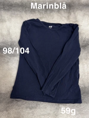 Marinblå långärmad topp - En enkel och stilren marinblå långärmad topp. Perfekt basplagg med rund hals och normal passform. Passar till det mesta och är lätt att matcha med andra plagg.🌸 Fint använt skick. Marinblå. Storlek 98/104