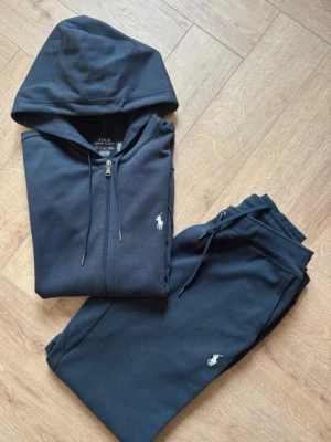 ralph lauren tracksuit navy  - Ralph lauren tracksuit i storlek S herr/ unisex. Stilren och elegant sett, som är i fint skick, nästintill ny o * Nypris: 2295 kr Skriv gärna vid eventuella funderingar Fraktas inom 24 timmarg . Skicket är som på bilderna Mått: Tröja Längd: 64 cm Bröst: 54 cm Axelbred: 46 cm Byxor: Längd: 98 cm Midja: 38 cm Ben öppning: 12 cm DEN ÄR ÄKTA. tar byte beror på vad det är och pris kan diskuteras och den har inga skador eller solbränna Hela är strl s byxan och tröjan s