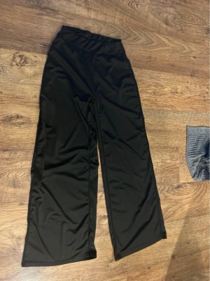 Svarta vida leggings med hög midja - Säljer ett par svarta leggings med hög midja och vida ben. De är tillverkade i ett stretchigt och mjukt material som ger en skön passform. Perfekta för dig som gillar en avslappnad och trendig stil.