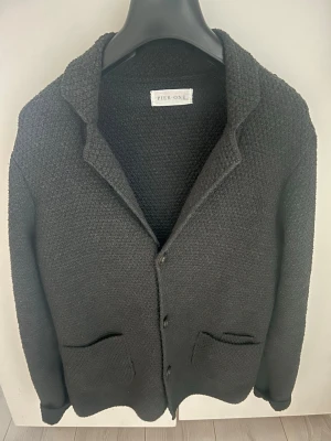 Stickad Kavaj - NYTT SKICK! Säljer en skitsnygg och fräsch stickad kavaj i färgen mörkgrå. Den är snygg att ha över en skjorta eller bara en vanlig T-shirt, eller som en lättare jacka över en hoodie tex. Storlek M. Snabb affär➡️bättre pris!