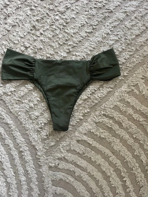 Mörkgröna bikiniunderdelar med rynk - Snygga mörkgröna bikiniunderdelar med rynkade sidor och hög skärning. Tillverkade i ett mjukt, stretchigt material som sitter bekvämt. Perfekta för lata dagar på stranden eller vid poolen. De är aldrig använda men lappen är tyvärr inte kvar längre. 💕