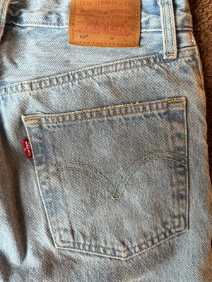 Levi's 501 ljusblå jeans - Klassiska Levi's 501 jeans i ljusblå denim med raka ben och femficksmodell. Snygga kontrastsömmar och ikonisk röd Levi's-tagg på bakfickan. Tillverkade i slitstarkt bomullsmaterial och har läderpatch bak i midjan.