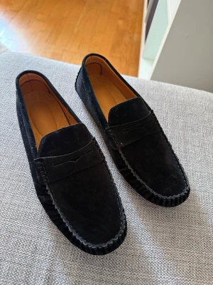 Svarta mockaloafers - Säljer ett par stilrena svarta loafers i mocka med klassisk pennyloafers-look. Skorna är o fint skick då de endast används 1 gång. Nypris 799