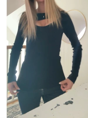 Svart långärmad topp med cut out - Helt ny, använd en gång svart långärmad topp med snygg cut out-detalj vid halsen.