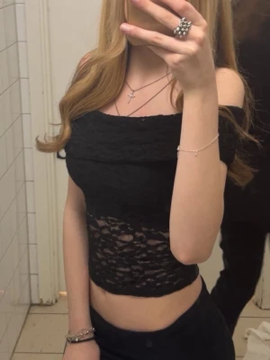 Svart offshoulder spets topp - Säljer en svart offshoulder topp med spetsdetaljer och croppad passform. den är genomskinlig vid magen men inte vid bysten. 