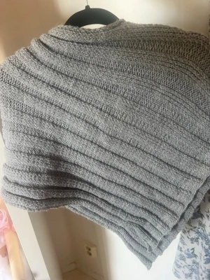 🩶 Handstickad grå poncho | Strl S | Unik - Säljer en fin handstickad grå poncho i storlek S. Eftersom den är egenstickad är den helt unik och har en mysig, tidlös känsla. Perfekt att bära över en tröja eller ett linne under kyligare dagar.