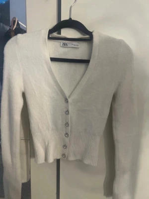 🤍 Vit kofta med pärl-/kristallknappar | Strl S | Nypris 600 kr - Säljer en superfin vit kofta i storlek S med eleganta pärl-/kristallknappar som ger en lyxig och klassisk känsla. Perfekt att bära över ett linne, klänning eller topp – passar både till vardag och fest.En tidlös och feminin kofta som passar året runt och är enkel att styla.