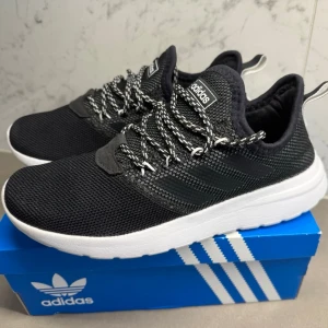 Svarta Adidas sneakers med vita sulor - Snygga svarta Adidas sneakers med stickad ovandel och vita, tjocka sulor. Skorna har svarta och vita mönstrade snören och diskreta Adidas-ränder på sidan. Perfekta för en sportig och avslappnad stil.
