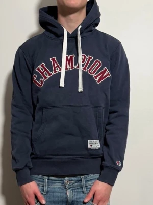 Marinblå vintage hoodie från champion - Mörkblå hoodie från Champion med ett simpelt men snyggt tryck. Tröjan är size S skick8/10. Passar perfekt nu till våren!! Modellen är 176cm lång väger 65kg.MVH zen_market