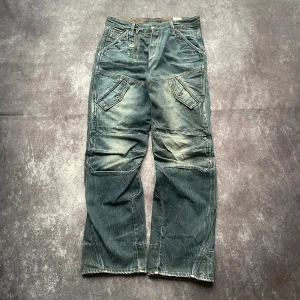 G-Star Raw R33/01 blå vintagejeans för herrar i storlek W32 L33 - Bekväm passform och slitstark, tekniskt skuren G-Star Raw-denim. W/L är uppskattade utifrån måtten.  Midja: 42 cm Benslut: 23 cm Lår: 33 cm Totallängd: 106 cm  Skickas inom ett dygn Spara på priset och frakten genom att sätta ihop ett paket  Mer information finns i min profil H2