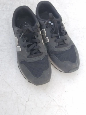 Svarta New Balance sneakers - Snygga svarta sneakers från New Balance med klassisk N-logga i vitt på sidan. Ovandelen är i mesh och mockaliknande material, och sulan är rejäl med bra grepp. Perfekta för dig som gillar streetwear och sportig stil. Pris kan diskuteras