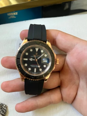 Svart och guld sportig klocka - Snygg klocka med svart urtavla och svart gummiband. Boetten är i guldton och har en markerad svart bezel. Urtavlan har tydliga index och datumvisning. Perfekt accessoar för dig som gillar en sportig men ändå stilren look.