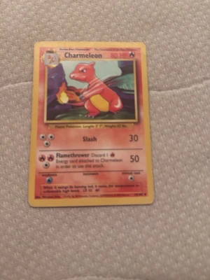 Charmeleon Pokémonkort - Charmeleon Pokémonkort från originalserien. Kortet har en gul ram, färgglad illustration av Charmeleon och text på engelska. Baksidan är blå med en Pokéball och Pokémon-loggan. Perfekt för samlare eller Pokémonfans.