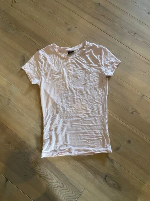 Rosa basic t-shirt från Gina Tricot - En enkel och klassisk rosa t-shirt från Gina Tricot i storlek XS. T-shirten har rund halsringning och korta ärmar. Perfekt att matcha med jeans eller kjol för en clean look.