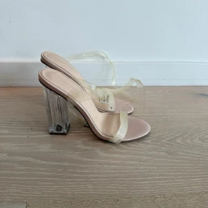 Pumps med transparent klack och remmar - Snygga pumps med transparent blockklack och genomskinliga remmar. Skon har en ljusrosa innersula och öppen tå. Perfekt för dig som vill ha en modern och trendig look med en twist. Klacken är stabil och ger extra höjd.