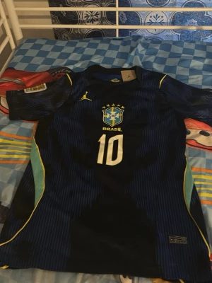 Blå Brasilien fotbollströja Neymar Jr - Säljer en äkta Brazil 26/27 world cup away blå fotbollströja med gula detaljer från Brasilien, Den har även prislapp,Den har nummer 10 och Neymar Jr på ryggen. Tröjan har korta ärmar, CBF-logga på bröstet och är tillverkad i ett lätt, ventilerande material perfekt för träning eller match.