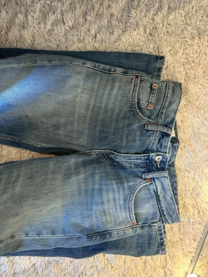 Ljusblå raka jeans med slitningar - Säljer ett par ljusblå baggy jeans med raka ben och klassisk femficksmodell. Jeansen har snygga slitningar och en något tvättad look. Perfekta för en avslappnad stil och passar till det mesta. Materialet är denim i bomull.