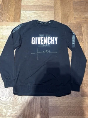 Svart sweatshirt Givenchy faith - Svart sweatshirt från Givenchy med tryck 'GIVENCHY' och 'faith' framtill. Tröjan har rund hals, ribbade muddar vid ärmslut och nederkant samt tryck på ärmarna. Tillverkad i mjukt bomullsmaterial och har en avslappnad passform.