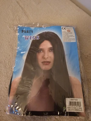 Svart lång peruk Party Wigs - Svart lång peruk från Party Wigs, perfekt för maskerad eller temafest. Peruken är rak och har en glans. Kommer i originalförpackning och är enkel att använda för att snabbt byta stil. Jag har andvänt den en gång.Det är inte de bästa kvalitet så därför säljer jag den billig