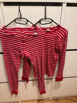 Rödvit randig pyjamas set Polarn O. Pyret XS - Supermysig pyjamas från Polarn O. Pyret i storlek XS. Setet består av långärmad tröja och byxor, båda i röd och vit randig design. Tillverkad i mjuk bomull med ribbade muddar vid ärmar och benslut. Perfekt för chillkvällar hemma.