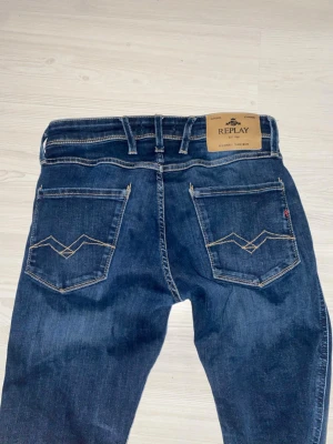 Replay blå jeans med broderade fickor - Säljer ett par blå jeans från Replay med snygga kontrastsömmar och broderade detaljer på bakfickorna. Klassisk femficksmodell och normal passform. Perfekta för dig som gillar en enkel men stilren look.