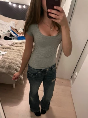 Grå basic t-shirt med urringning  - En enkel och stilren grå t-shirt med rundad halsringning och korta ärmar. Modellen är figurnära och passar perfekt till jeans eller kjol. Tillverkad i mjukt bomullsmaterial för en bekväm känsla hela dagen.