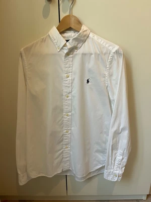 Vit Ralph Lauren skjorta i storlek 164-170cm (14-16 år)  - Säljer en vit Ralph Lauren skjorta i storlek 164-170cm (14-16 år) för att den nu är för liten. Skjortan i sig är inte använd många gånger och nästan i nyskick 