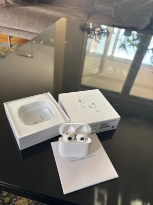 AirPods(3rd gen - Säljer ett par vita AirPods  med trådlöst laddningsetui. Hörlurarna har en stilren och kompakt design i blank plast och levereras i originalförpackning med tillhörande tillbehör. Perfekta för musik, samtal och träning.