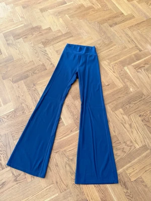 Blå utsvängda leggings - Snygga blå leggings med hög midja och utsvängda ben. Stretchigt material som sitter bekvämt och ger en trendig siluett. Perfekta för dig som gillar en retroinspirerad look och vill sticka ut lite extra.