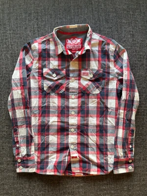 Superdry skjorta ~ sällsynt  - Säljer nu denna sjukt snygga Superdry skjortan | st M ~ 175–185cm | marinblå/röd/vit rutig design som passar perfekt till sommar och höst! Modellen produceras inte längre och är därav väldigt sällsynt. Kan även gå ner lite i pris vid snabb affär🍁🫶
