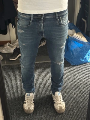 Blå slitna jeans från Replay - Säljer ett par blå jeans från Replay med slitningar och lätt tvättad look. Modellen är slim fit med klassiska fem fickor. Sjukt snygga till hösten!
