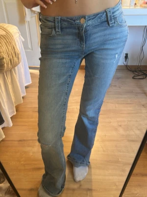 Blå bootcut jeans med broderad ficka - Säljer ett par ljusblå bootcut jeans med snygg broderad detalj och nitar på bakfickan. Jeansen har broderade fickor samt mid waist midja. Från Gina💕har använt ca 2 gånger