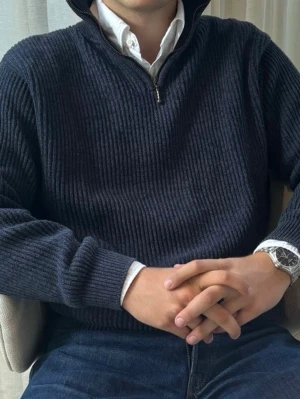 Mörkblå ribbstickad tröja med halvzip - Mörkblå stickad tröja med ribbad struktur och halv dragkedja vid halsen. Tröjan har hög krage och långa ärmar med breda muddar. Perfekt att bära över en skjorta för en stilren look.