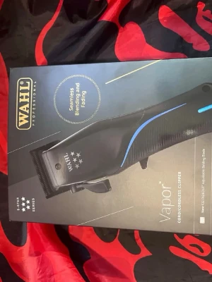 Wahl Vapor hårtrimmer svart/blå - Wahl Vapor är en professionell hårtrimmer i svart med blå detalj, perfekt för sömlös övergång och fading. Den är sladdlös/sladdansluten och levereras med flera tillbehör för styling. Ergonomisk design och justerbart blad för precision.
