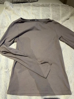 Beige ribbad långärmad topp 157 - Säljer en beige ribbad långärmad topp från 157 i storlek XS. Toppen har en enkel och stilren design med rund halsringning och smal passform. Perfekt att matcha med jeans eller kjol för en clean look.