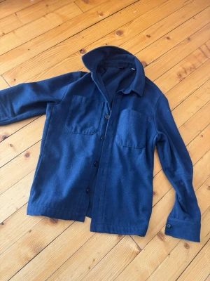 D’once de la sense overshirt  - Ny kr 1000 kr men säljs 200 kr för lite håll Stilren mörkblå overshirt i mjukt tyg med två stora bröstfickor och knäppning framtill. Klassisk krage och knappdetaljer vid ärmslut. Perfekt lager-på-lager-plagg för en avslappnad look.