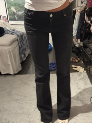 Svarta bootcut/straight jeans - Säljer ett par svarta  jeans med medel hög midja. Jeansen har raka ben med lätt utsvängning nedtill. Sitter jättefint på men lite för långa för mig som är 164,5 därför har jag små klackar på bilden! 