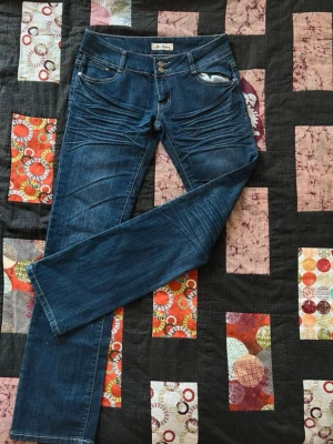 Blå jeans från Miss Botons - Snygga blå jeans från Miss Botons med raka ben och dubbla knappar i midjan. Jeansen har dekorativa sömmar och slitningar framtill samt klassiska fickor. Perfekta för dig som gillar en trendig och avslappnad stil.