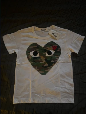 Vit Comme des Garçons Play t-shirt - Säljer en helt ny vit Comme des Garçons Play t-shirt i small. Ovanpå hjärtat sitter en liten röd detalj med ögon. Skriv om ni har frågor.