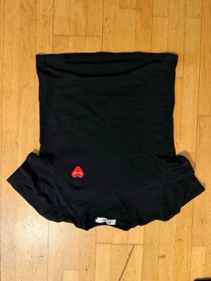 Svart t-shirt med rött hjärta - Säljer en svart t-shirt i bomull med ett broderat rött hjärta med ögon på bröstet. Klassisk passform och korta ärmar, perfekt till vardagslooken. Enkel men ändå unik detalj som sticker ut.