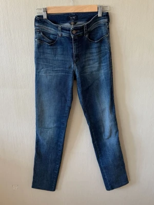 Armani Jeans Mörkblå skinny jeans med slitningar - Snygga mörkblå skinny jeans från Armani Jeans med lätt slitna detaljer och klassisk femficksdesign. Jeansen har normal midja och smal passform hela vägen ner. Materialet är stretchigt denim som ger en bekväm känsla och följer kroppen.0096